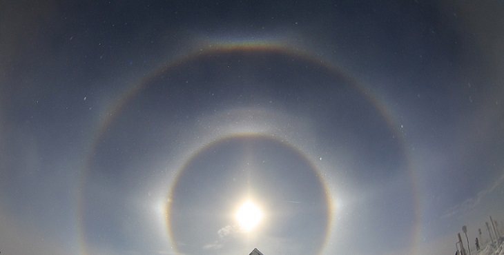 Image of the Sun in the center point with double circles of reflecting light around it, surrounded by snow background. Earth Archive #4